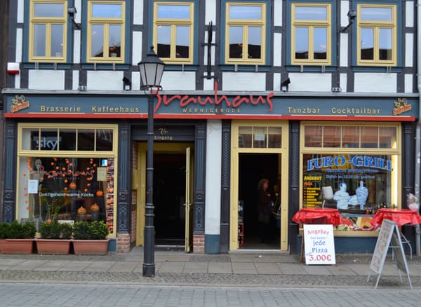 Außenansicht des Brauhauses Wernigerode: Fachwerkfassade mit gelben Fensterrahmen, rotem Brauhaus-Schriftzug und Eingang zur Breiten Straße